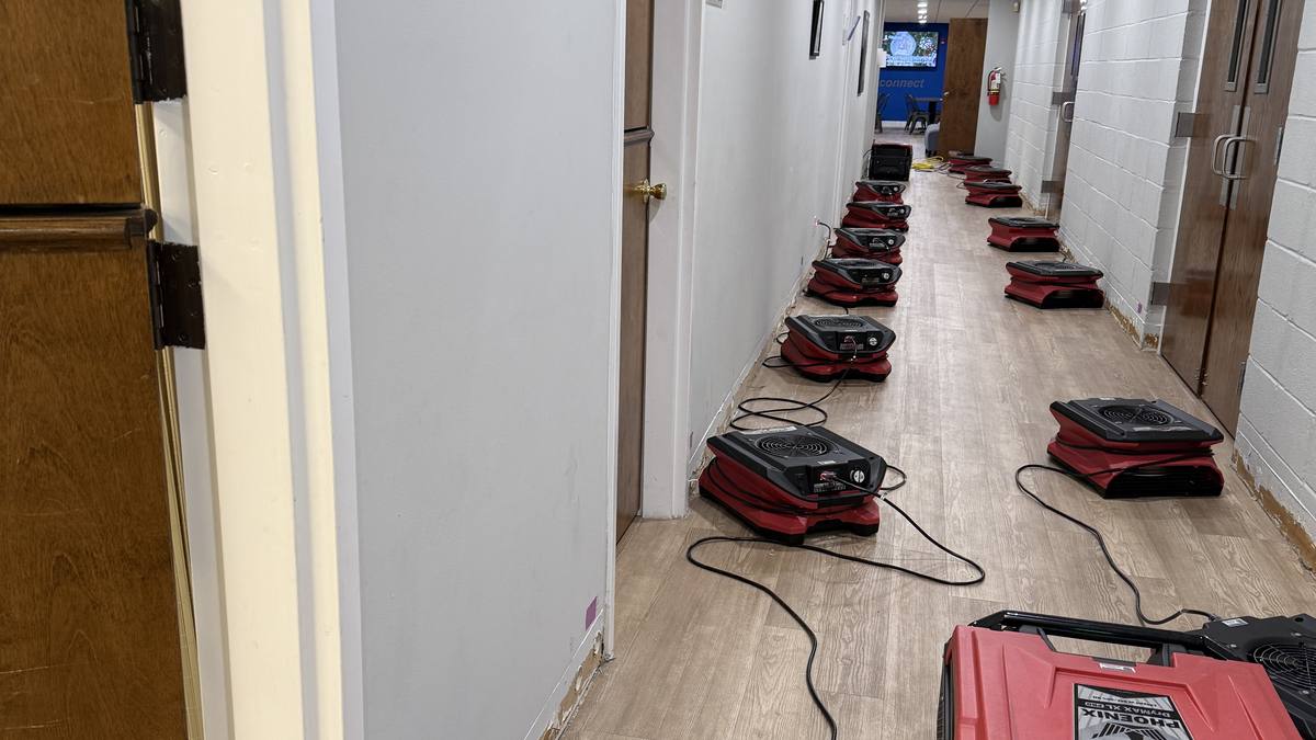 Air movers lined down a hallway after storm flooding in Charleston